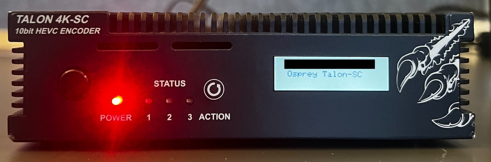 The image highlights the author holding the Osprey Talon encoder where the display on the encoder says the stream has started and the power button is lit up.